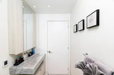 a white kitchen with a sink and a door at Luxury Yorkville Two Bedroom Condo With Views and Parking in Toronto