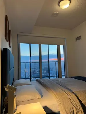 a bedroom with a large bed with a large window at Modern 1 bedroom with private bathroom near Toronto airport in Toronto