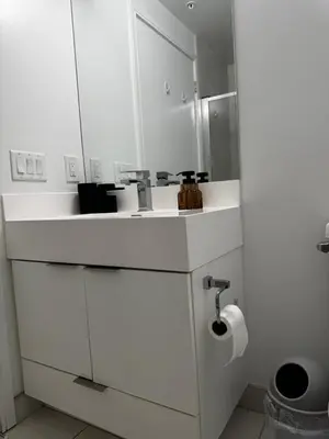 a white bathroom with a sink and a toilet paper roll at Modern 1 bedroom with private bathroom near Toronto airport in Toronto
