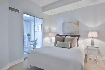 a white bedroom with a large white bed with pillows at Bloor Yonge Cozy 1BR And Den Free Parking in Toronto
