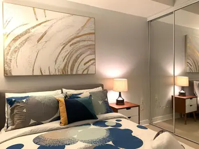 a bedroom with a bed with a painting on the wall at Bloor Yonge Cozy 1BR And Den Free Parking in Toronto