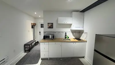 a kitchen with white cabinets and a sink and a refrigerator at Cozy Studio Retreat in Scenic Georgina, Canada in Georgina