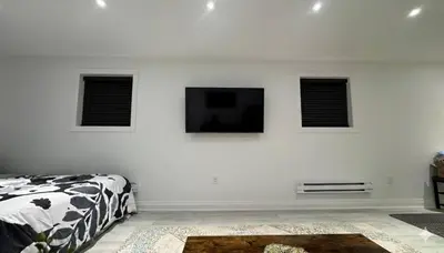 a white room with a bed and a flat screen tv at Cozy Studio Retreat in Scenic Georgina, Canada in Georgina
