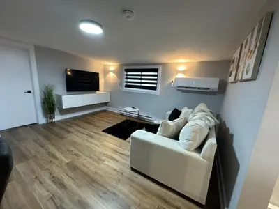 a living room with a white couch and a television at Modern 1 Bdrm with Laundry, BBQ, Deck in Welland