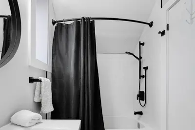 a bathroom with a shower with a black shower curtain at Modern 1 Bdrm with Laundry, BBQ, Deck in Welland