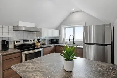 a kitchen with a stainless steel refrigerator and a counter at Modern 1 Bdrm with Laundry, BBQ, Deck in Welland