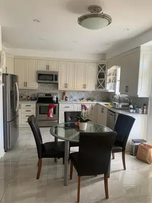 a kitchen with a table and chairs and a refrigerator at Cozy House in Richmond Hill