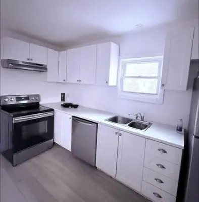 a kitchen with white cabinets and a sink and a stove at Cozy Fort Erie crystal Beach house in Fort Erie