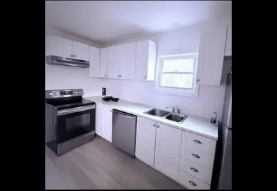 a kitchen with white cabinets and a sink and a stove at Cozy Fort Erie crystal Beach house in Fort Erie