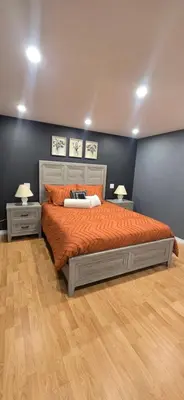 a bedroom with a bed with orange sheets and two tables at Paradise Haven in Arthur