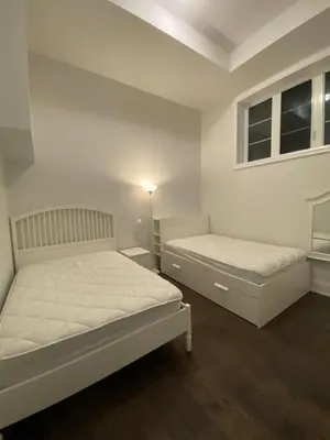two beds in a room with white walls and wood floors at Modern Living near Yonge St in Toronto