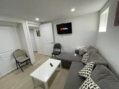 a living room with a couch and a tv on the wall at The Pantry Suite - Cozy Basement Stay in Mississauga