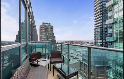 a balcony with chairs and a view of a city at Liberty Village Condo Lake and BMO Field View in Toronto