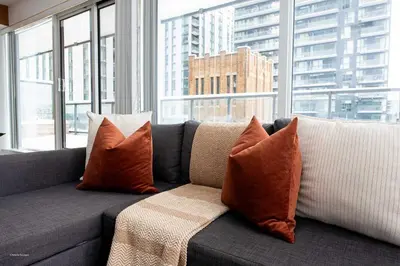 a couch with orange pillows in front of a window at Stunning 2BR Downtown Condo w Huge Private Patio in Toronto