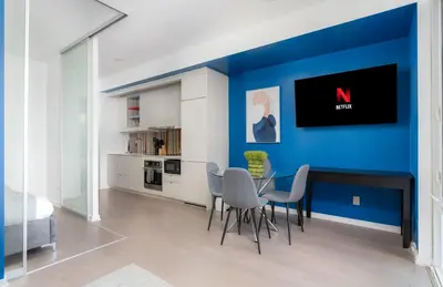 a dining room with a blue wall and a table and chairs at Designer 1BR Condo Entertainment District in Toronto