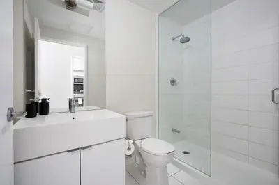 a white bathroom with a toilet and a shower at Modern CityPlace 2BR Balcony & Free Parking in Toronto