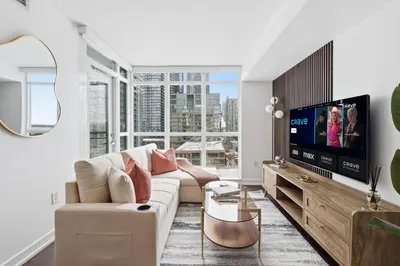 a living room with a couch and a tv at Modern Downtown Retreat Cozy Living & City Views in Toronto