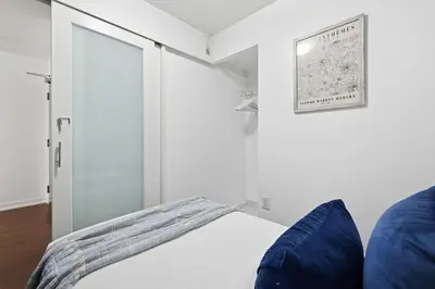 a white bedroom with a bed with blue pillows at Modern Downtown Retreat Cozy Living & City Views in Toronto