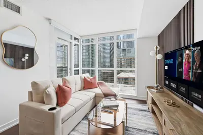 a living room with a couch and a tv at Modern Downtown Retreat Cozy Living & City Views in Toronto