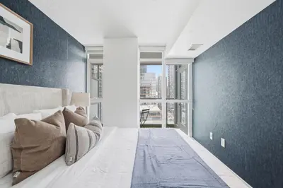 a bedroom with a bed with a blue accent wall at Modern Downtown Retreat Cozy Living & City Views in Toronto