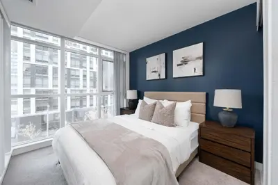 a bedroom with a large bed and a blue wall at Modern CityPlace Sky Home 2BR 2BA & Balcony in Toronto