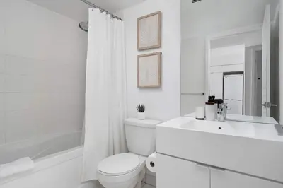 a white bathroom with a toilet and a sink and a tub at Modern CityPlace Sky Home 2BR 2BA & Balcony in Toronto