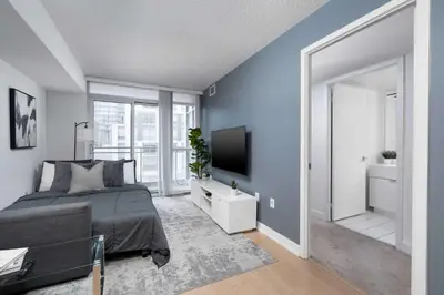 a bedroom with a bed and a flat screen tv at Modern CityPlace Sky Home 2BR 2BA & Balcony in Toronto