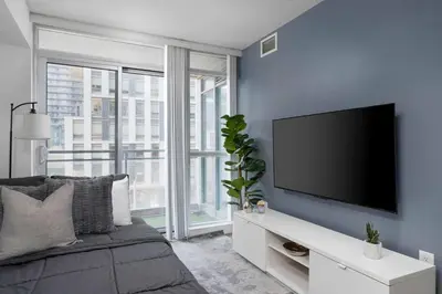 a bedroom with a flat screen tv on a blue wall at Modern CityPlace Sky Home 2BR 2BA & Balcony in Toronto
