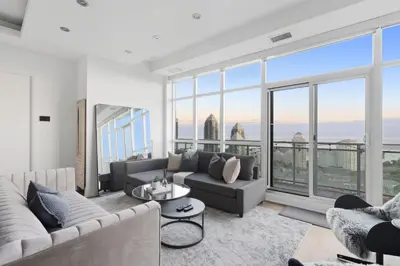 a living room with a couch and large windows at Luxury Parklawn Penthouse Breathtaking Lake View in Toronto