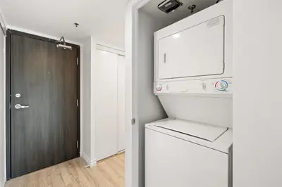 a kitchen with a washer and dryer next to a door at Downtown Oasis Sleek Suite by Yonge Dundas Sq in Toronto
