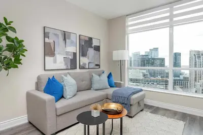 a living room with a couch and a large window at Bright 1BR Suite with Patio & CN Tower Views in Toronto