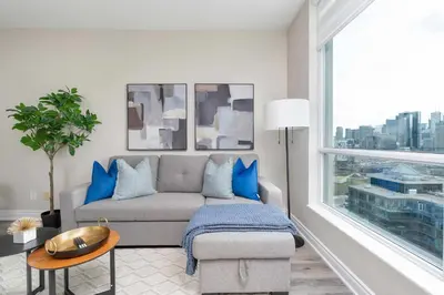 a living room with a couch and a large window at Bright 1BR Suite with Patio & CN Tower Views in Toronto