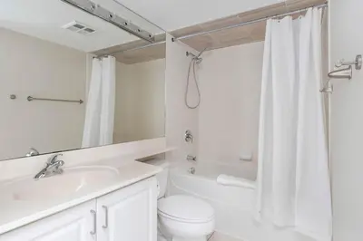 a white bathroom with a toilet and a sink at Bright 1BR Suite with Patio & CN Tower Views in Toronto