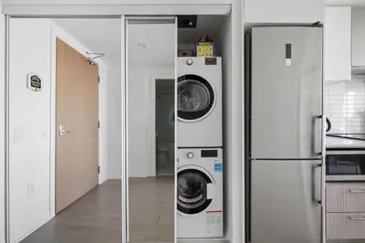 a kitchen with a washer and dryer next to a refrigerator at Stunning Family-Friendly Parking & City Views in Toronto