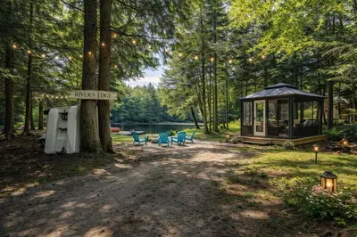 a park with a gazebo and a sign on a tree at Waterfront Muskoka Cottage with FirePit, BBQ and Canoes in Bracebridge