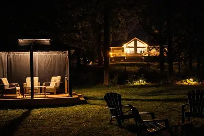 a gazebo with chairs and a house at night at Waterfront Muskoka Cottage with FirePit, BBQ and Canoes in Bracebridge