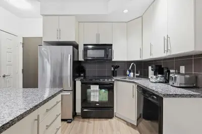 a kitchen with white cabinets and black appliances at Cozy 1BR Condo w Private Patio for Morning Coffee in Toronto