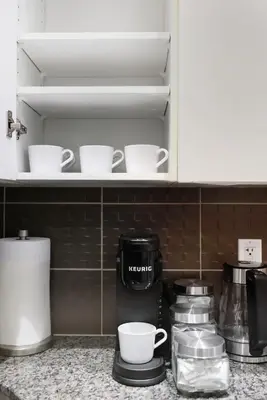 a kitchen counter with cups and coffee cups on a shelf at Cozy 1BR Condo w Private Patio for Morning Coffee in Toronto
