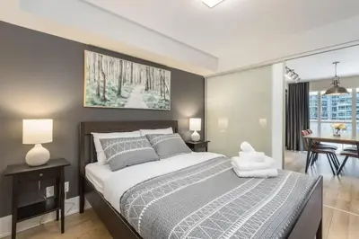 a bedroom with a large bed and a dining room at Modern 1BR Retreat with Balcony & Parking in Toronto