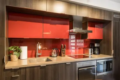 a kitchen with red cabinets and a stainless steel sink at Modern 1BR Retreat with Balcony & Parking in Toronto