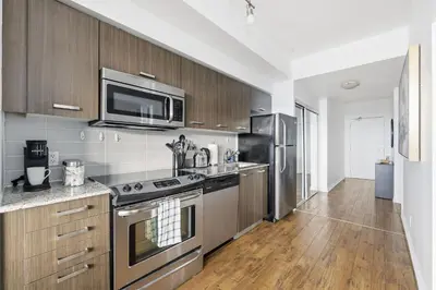 a kitchen with stainless steel appliances and wooden cabinets at Chic Bay St Condo Skyline Views 55 TV in Toronto