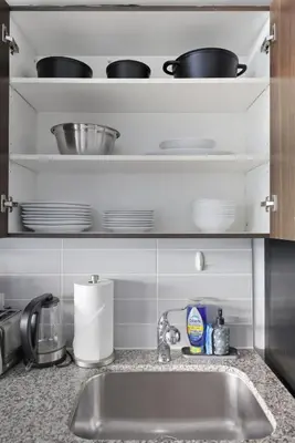 a kitchen counter with a sink and dishes on shelves at Chic Bay St Condo Skyline Views 55 TV in Toronto