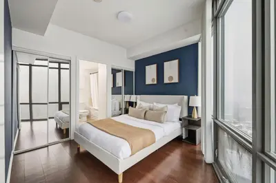 a bedroom with a king sized bed with blue walls at Designer Bay Street Condo Sleep 6 in Toronto
