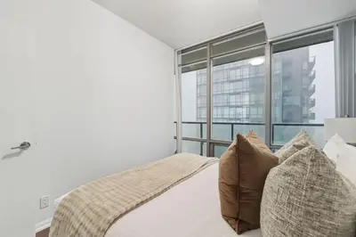 a bedroom with a bed with pillows and a window at Designer Bay Street Condo Sleep 6 in Toronto