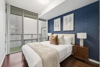 a bedroom with a large bed with a blue wall at Designer Bay Street Condo Sleep 6 in Toronto