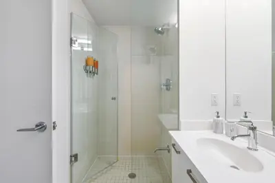 a white bathroom with a sink and a shower at Designer Bay Street Condo Sleep 6 in Toronto