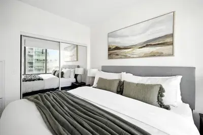 a white bedroom with two beds and a window at Financial District Oasis Sleeps 5 55 TV in Toronto