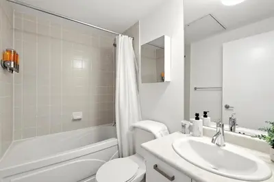 a white bathroom with a sink and a toilet at Financial District Oasis Sleeps 5 55 TV in Toronto
