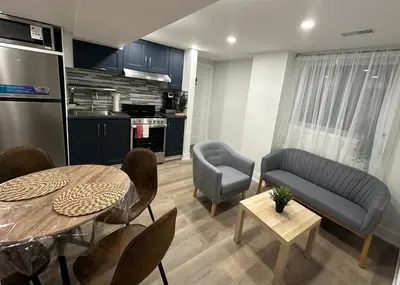a living room with a table and chairs and a kitchen at Cozy Parkside 2 Bedroom Basement Suite in Vaughan
