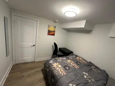 a bedroom with a bed and a chair in it at Cozy Parkside 2 Bedroom Basement Suite in Vaughan
